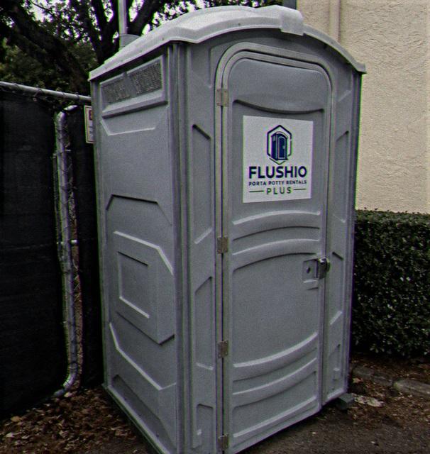 Standard portable toilet rental unit placed beside a building wall